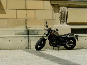 Motorrad seitlich vor Altbaufassade auf hellem Pflaster, ruhiges Tageslicht