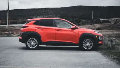 Roter Kompakt-SUV im Seitenprofil am Rand einer Landstraße bei Tageslicht