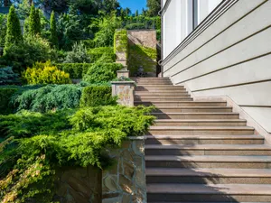 Zuwegung mit Granitstufen, Natursteinmauer und geschnittenen Nadelgehölzen am Wohnhaus