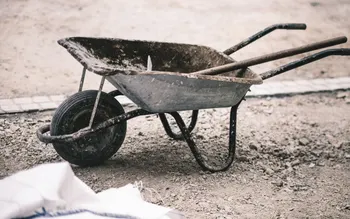 Rohzustand vor dem Umbau: gebrauchte Schubkarre auf verdichtetem Schotter neben Baumaterial