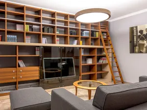 Raumhohe Bücherwand aus Holz mit angesetzter Leiter, offene Fächer und Schubladen