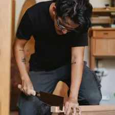Tischler sägt konzentriert mit einer Feinsäge an einem Werkstück in der Werkstatt