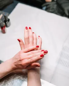 Fertige Maniküre in kräftigem Rot, Hand ruht auf hellem Tuch