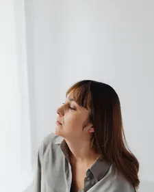 Heilpraktikerin im Profil vor hellem, neutralem Hintergrund, ruhiger Ausdruck.