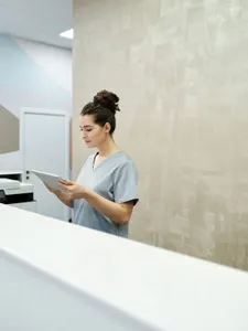 Simon, Medizinische Fachangestellte, mit Tablet am Empfangstresen