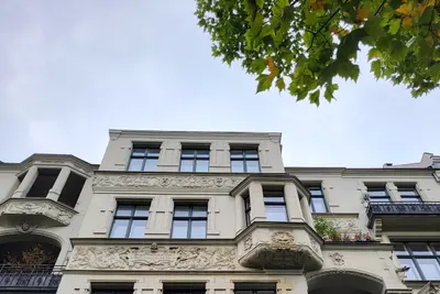 Fassade eines Berliner Altbaus: Stuck, Erker, Balkone, davor Ahornlaub