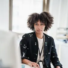 Mitarbeiterin der Hausverwaltung am Schreibtisch im hellen Büro, Dienstausweis am Band