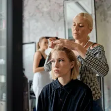 Stylistin hebt eine Strähne mit dem Kamm ab, konzentriert bei der Arbeit