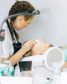 Lash-Artist arbeitet konzentriert an einer liegenden Kundin