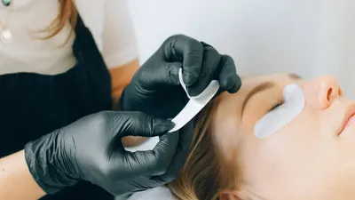 Lash-Artist setzt Wimpernverlängerungen bei einer liegenden Kundin