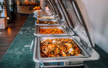 Reihe offener Chafing Dishes mit warmgehaltenen Speisen kurz vor dem Service
