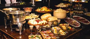 Aufgebautes Buffet mit Canapés, Käse und Chafing Dishes im warmen Abendlicht