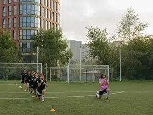 Mannschaft beim Aufwärmen mit Ausfallschritten auf dem Kunstrasenplatz, dahinter Wohnhäuser